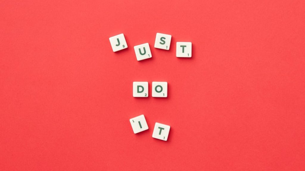Motivational phrase 'Just Do It' spelled with Scrabble letters on a red background.